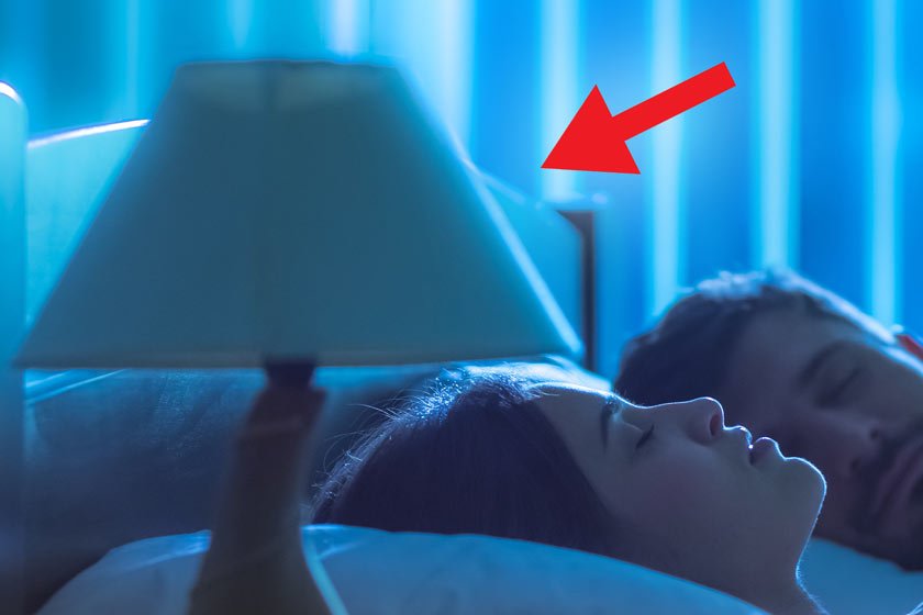 Eine Frau schläft im Bett, denben eine ausgeschaltete Nachttischlampe