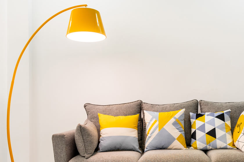 Eine gelbe Lampe und ein Sofa mit Kissen.